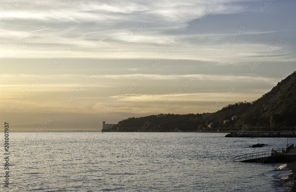 View of the romantic gulf of Trieste and the beautiful Miramare Castle at sunset. Miramare Castle is a 19th-century castle built for Austrian Archduke Ferdinand Maximilian and his wife