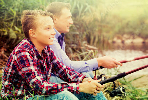 Father and son fishing on river