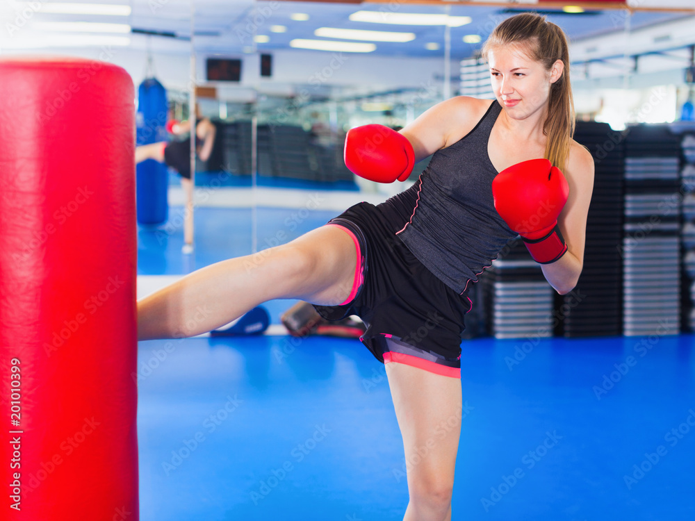 Woman boxer is training kick in box gym.