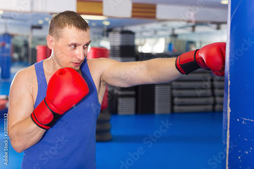 Man is training with punching bag in box gym © JackF