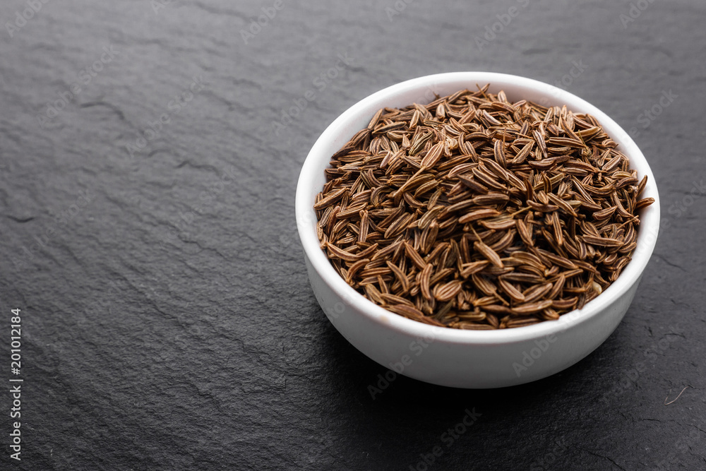 Seeds of cumin on a dark stone background Seeds of cumin on a dark stone background