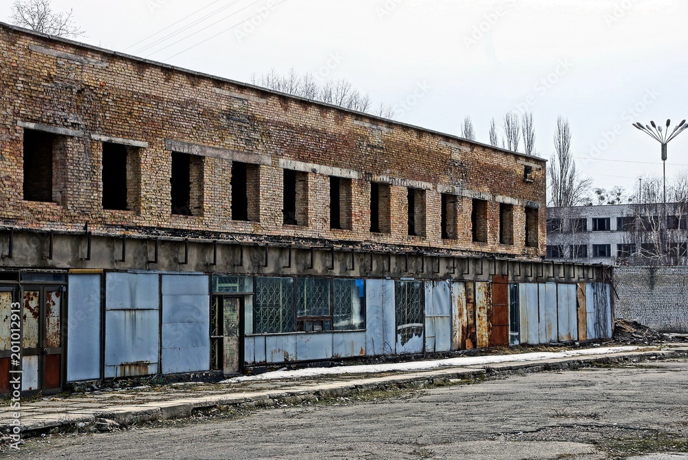 ruins of a brick building with empty windows behind an iron fence