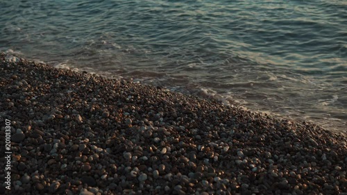 Close up shot of a blue waves of a beautiful sea crushing onto pebble beach shore. Art of the nature. photo