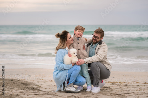 Happy family on a beach. The family walks on a beach with a dog.