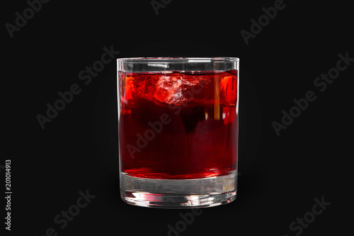 Single-color transparent cocktail, refreshing in a low glass with ice cubes with taste of berries, cherries, strawberries, grapefruit. Side view Isolated black background. Drink for the menu