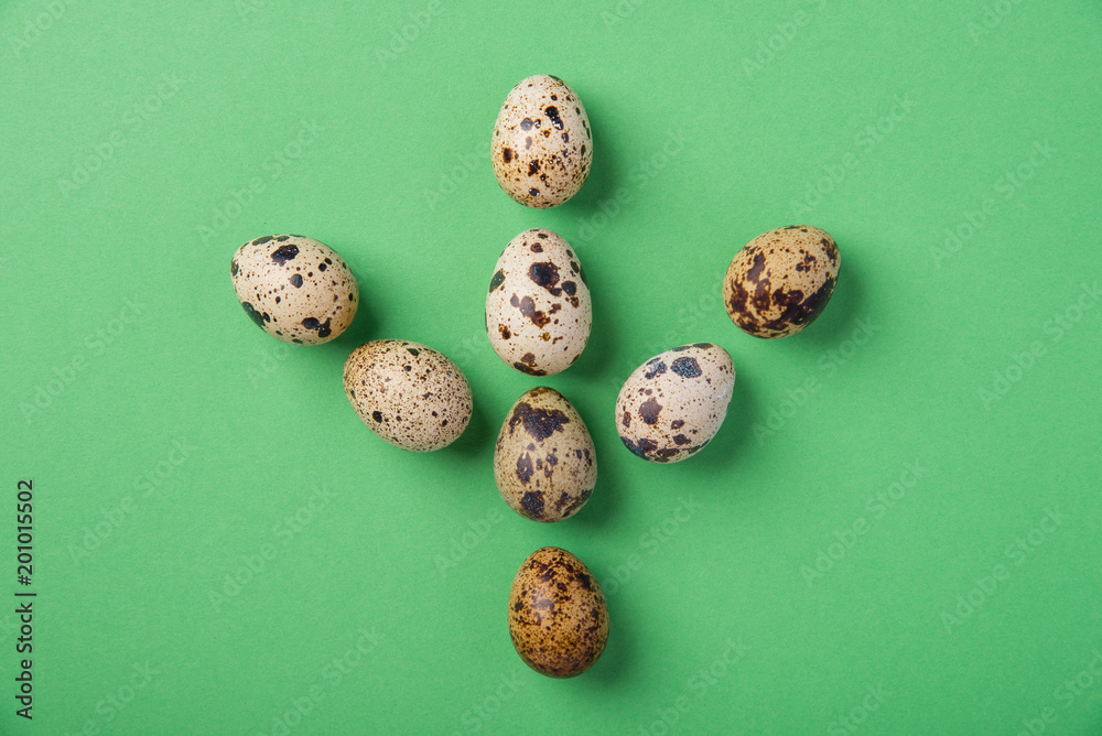 Beautiful fresh quail eggs in the form of a footprint or paw of a bird on a green background Beautiful fresh quail eggs in the form of a footprint or paw of a bird on a green background