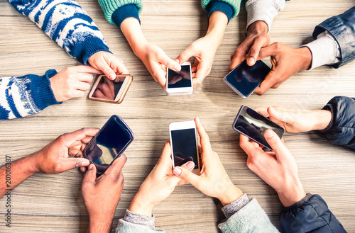 Hands circle using phones on table top view - Multiracial group of people holding mobile devices sitting around at office desk - Concept  of modern technology addiction