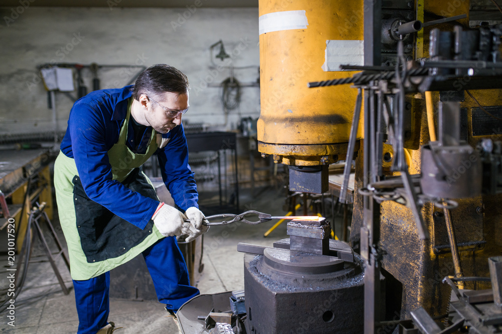 A man works in a smithy. A man works in a smithy.