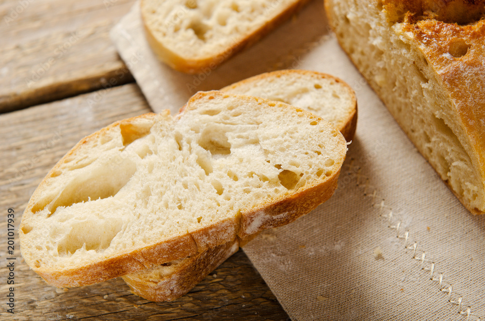Ciabatta bread. Slices of ciabatta on wooden table on linen cloth. Rustic style, italian. Top view, background Ciabatta bread. Slices of ciabatta on wooden table on linen cloth. Rustic style, italian. Top view, background