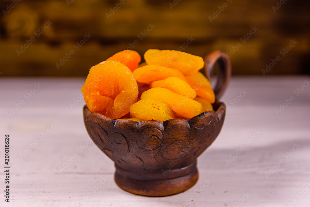 Ceramic bowl with dried apricots on wooden table Ceramic bowl with dried apricots on wooden table