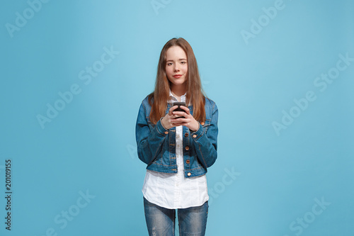 The happy teen girl standing and smiling against blue background.