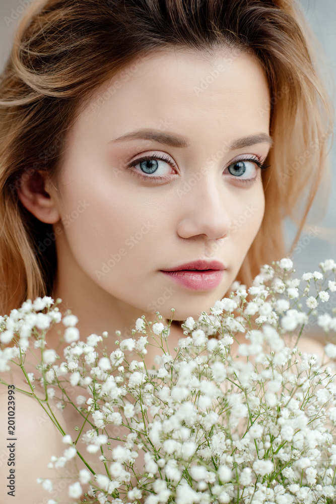 close-up portrait of beautiful young woman holding white flowers and looking at camera close-up portrait of beautiful young woman holding white flowers and looking at camera
