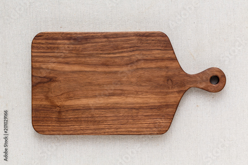 Fototapeta Walnut handmade wood cutting board on the linen