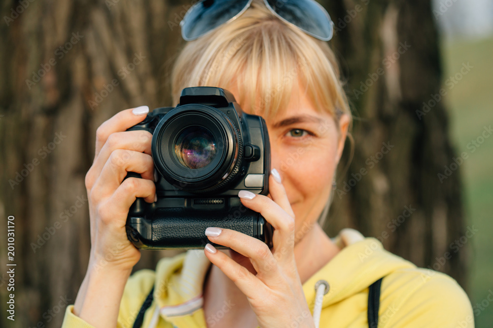 Girl with professional camera in hands. Close up of female photographer in park. Girl with professional camera in hands. Close up of female photographer in park.