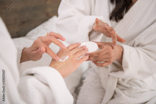 Moisturizer for skin. Close up of female hands with moisturizing cream being applied on them