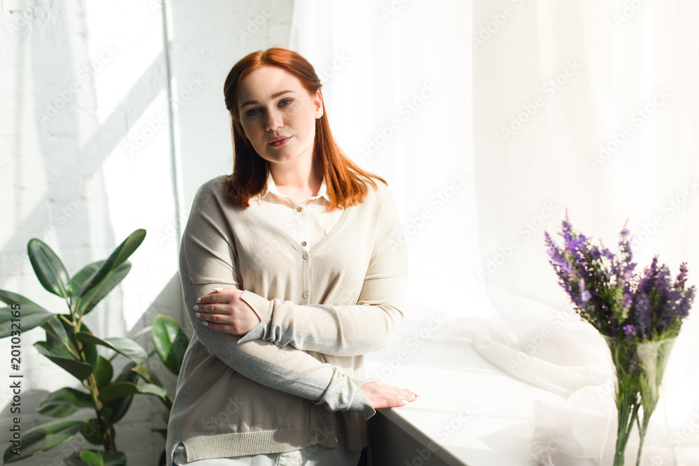 beautiful girl standing near window and looking at camera at home beautiful girl standing near window and looking at camera at home