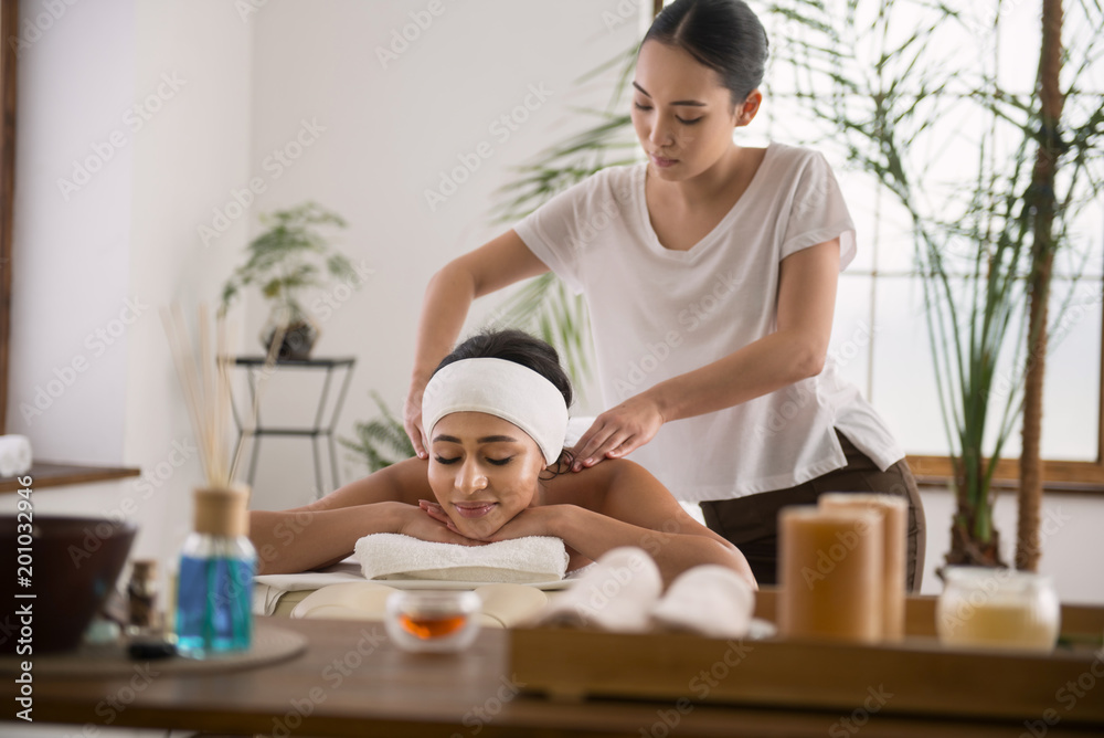 Time to relax. Positive delighted woman enjoying the massage while resting in the beauty salon