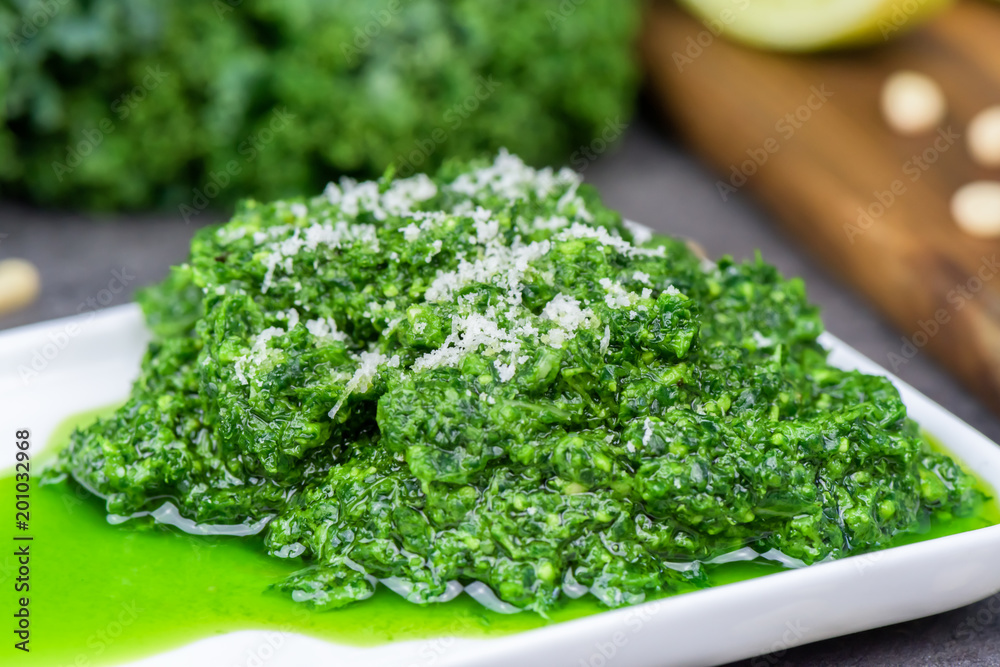 Pesto made from kale, cheese grana padano, lime, pine nuts and garlic - close up Pesto made from kale, cheese grana padano, lime, pine nuts and garlic - close up