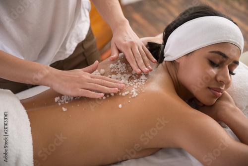 Special procedure. Beautiful young woman closing her eyes while enjoying the massage in the spa salon