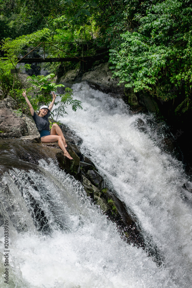 woman with outstretched arms resting on rock near Aling-Aling Waterfall, Bali, Indonesia woman with outstretched arms resting on rock near Aling-Aling Waterfall, Bali, Indonesia