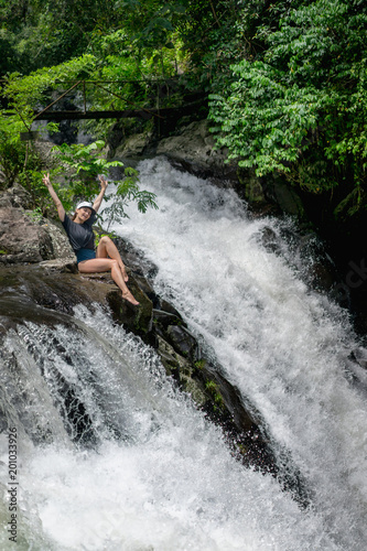 woman with outstretched arms resting on rock near Aling-Aling Waterfall  Bali  Indonesia