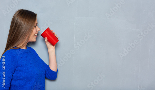 Girl dressed in casual blue wear holding red coffee cup.