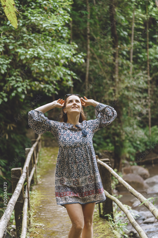 beautiful woman in dress standing on bridge with green plants on background, Bali, Indonesia beautiful woman in dress standing on bridge with green plants on background, Bali, Indonesia