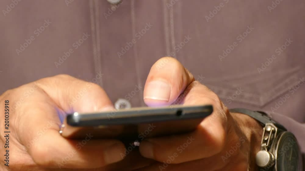 Men fingers typing on a touch screen smartphone, using the smartphone in close-up Men fingers typing on a touch screen smartphone, using the smartphone in close-up
