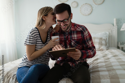 Young attractive couple using tablet in bedroom