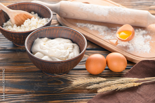 close-up view of cottage cheese, wheat ears, sour cream, eggs and flour on wooden table