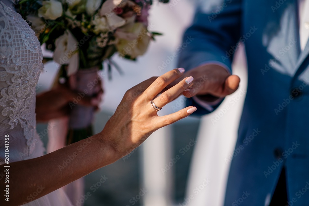 A groom puts the ring on the finger of bride