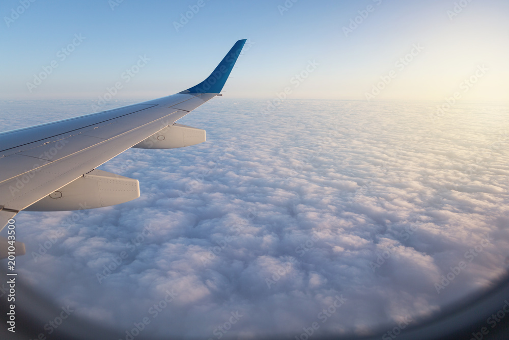 above the clouds, view from the airplane, visible wing elements and part of the porthole, concept travel above the clouds, view from the airplane, visible wing elements and part of the porthole, concept travel