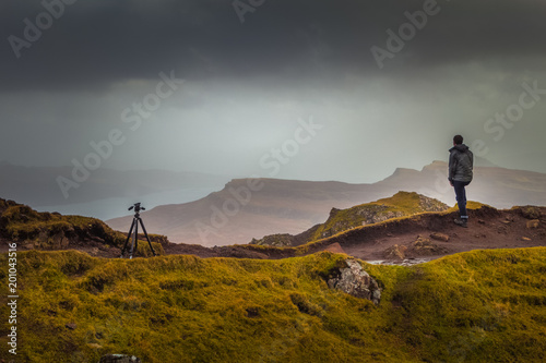 Man In Rain Jacket Looking Into The Distant Landscae From Top of Scottish Mountain