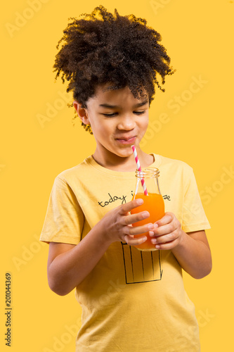 Cute little boy drinking orange juice with a straw