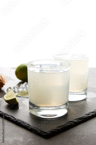 Close up view of refreshing caipirinha cocktails with lime on tabletop on white