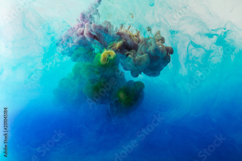 full frame image of mixing of blue, turquoise and yellow paints splashes in water