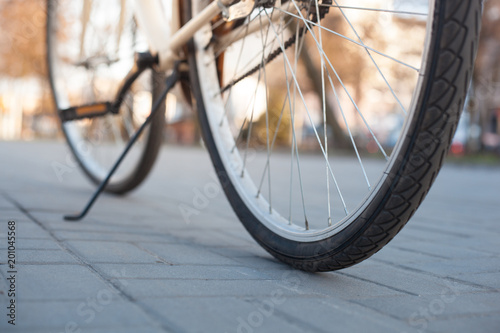 Beige bicycle wheels that stand on the sidewalk tile on the alley