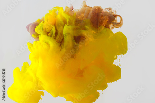 close up view of mixing of yellow, purple and brown paints splashes in water isolated on gray