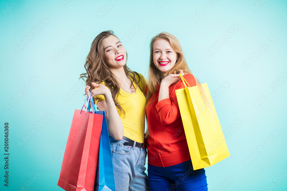 Beautiful girls with shopping bags are looking at camera and smiling while doing shopping Beautiful girls with shopping bags are looking at camera and smiling while doing shopping