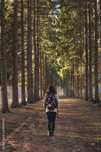 one girl stands in the middle of a pine tree tunnel in a spring Park
