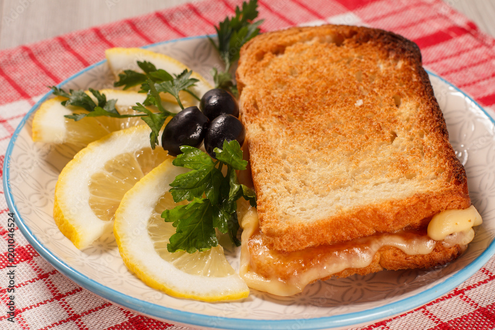 Good and delicious food and beverages for breakfast. Toast with butter and cheese, slices of lemon and olives on plate Good and delicious food and beverages for breakfast. Toast with butter and cheese, slices of lemon and olives on plate
