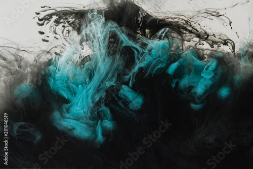 close up view of mixing of light gray, turquoise and black paints splashes in water isolated on gray