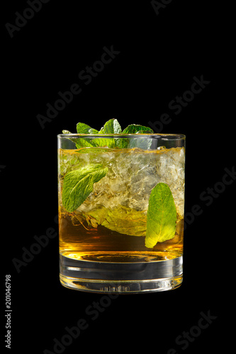Transparent one-color cocktail in a low glass with crushed ice frappe with mint leaves with melon, pear, apple taste. Side view Isolated black background. Drink for the menu restaurant, bar, cafe