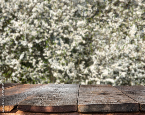 Sunny spring background with white flowers and empty wooden table