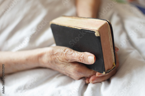 Hands of a senior woman on cane. Senior lying in a bed.