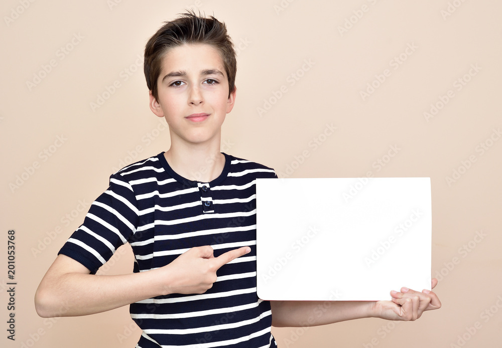 Young boy holding and showing with the index finger blank white paper Young boy holding and showing with the index finger blank white paper