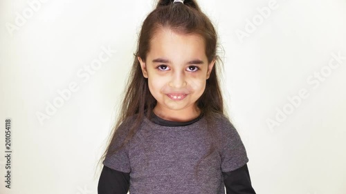 Little cute caucasian girl looking at camera, angry and smiling, portrait, white background 50 fps