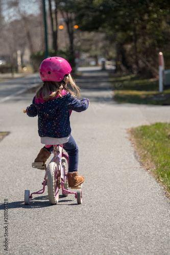 Little girl in pink helmet riding a training bike © juancramosgonzalez