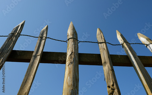 Ein rustikaler Holzzaun mit blauem Himmel im Hintergrund photo