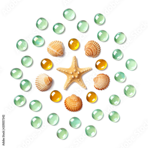 Pattern in the form of a circle made of shells  starfish and green and yellow glass beads isolated on white background